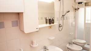 Een badkamer met twee wastafels, toilet, bidet en douche.