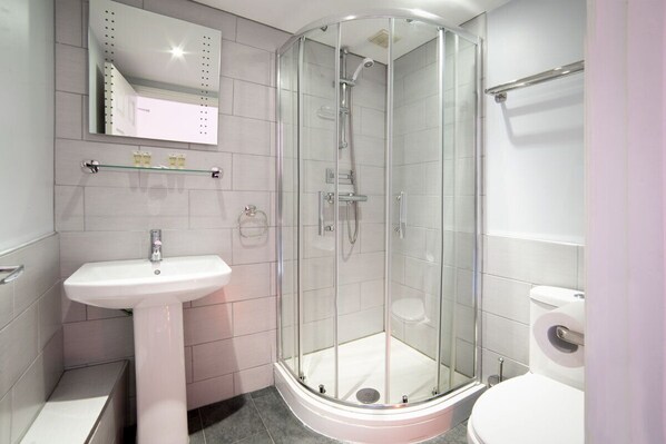 A modern bathroom with a glass-enclosed shower, a pedestal sink, and a toilet.