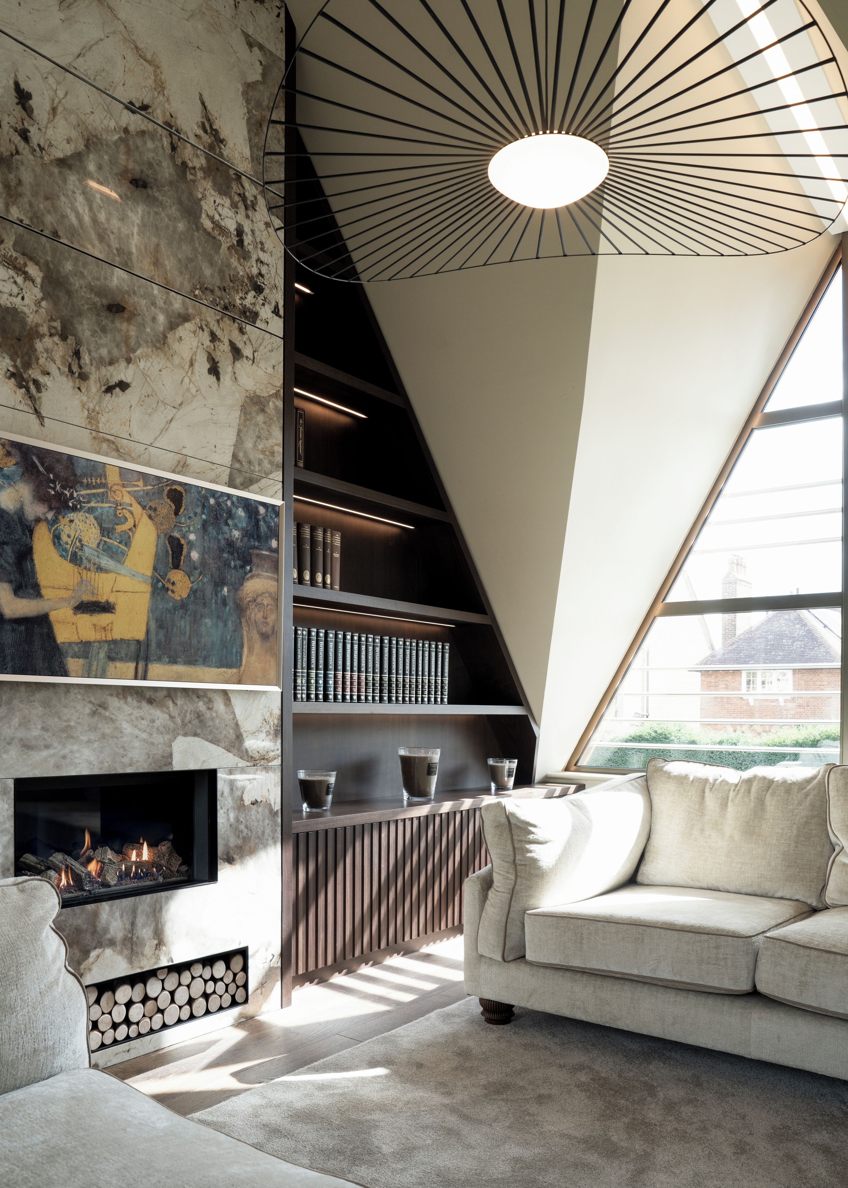 A modern interior with a fireplace, bookshelves, a sofa, and a large window.