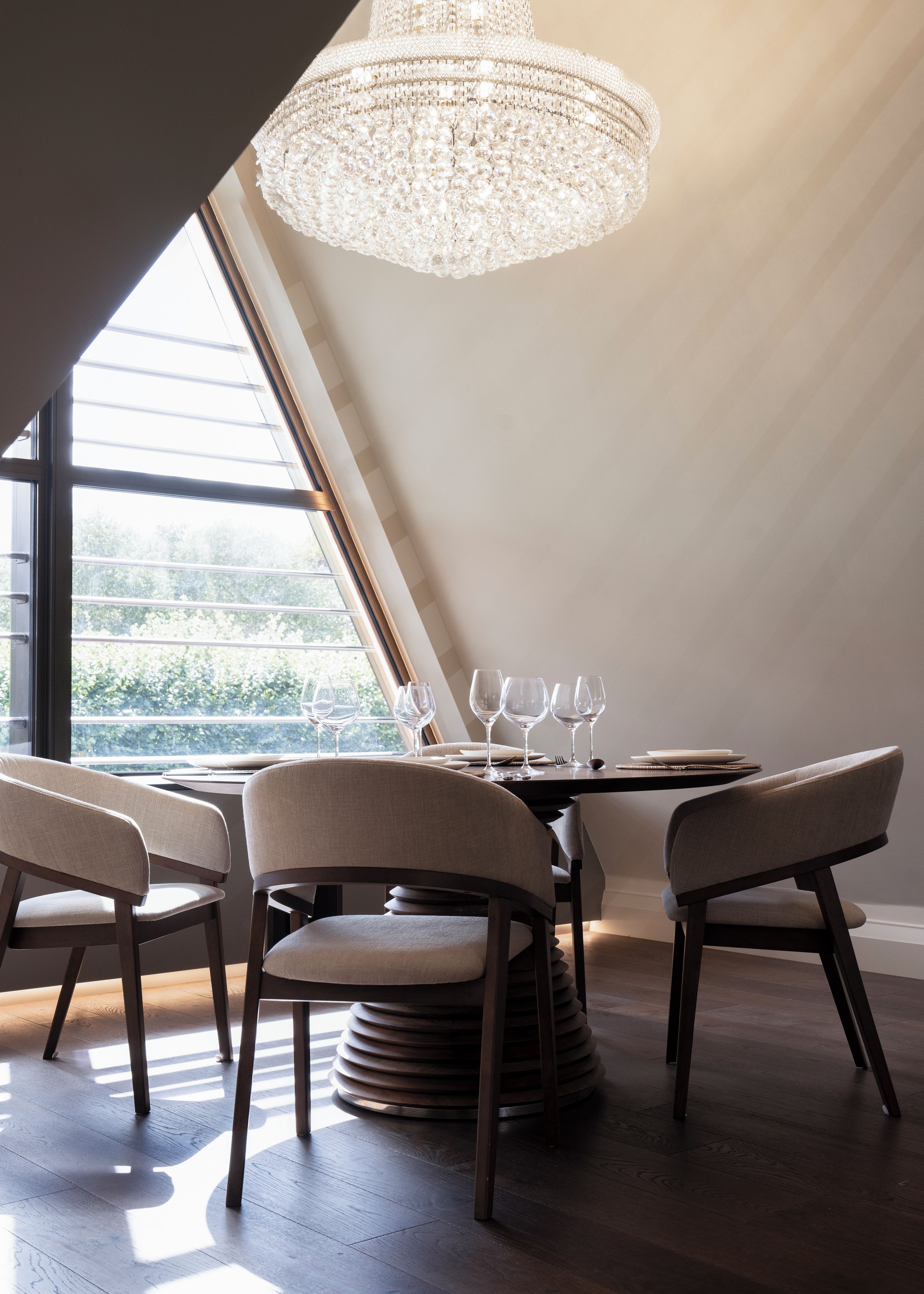 A dining area with a chandelier, round table, and chairs.
