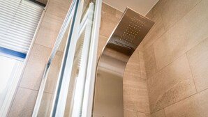 Ein modernes Badezimmer mit Dusche, geflieste Wände und einem Fenster mit Jalousien.