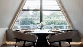A dining area with a round table, chairs, and a chandelier.