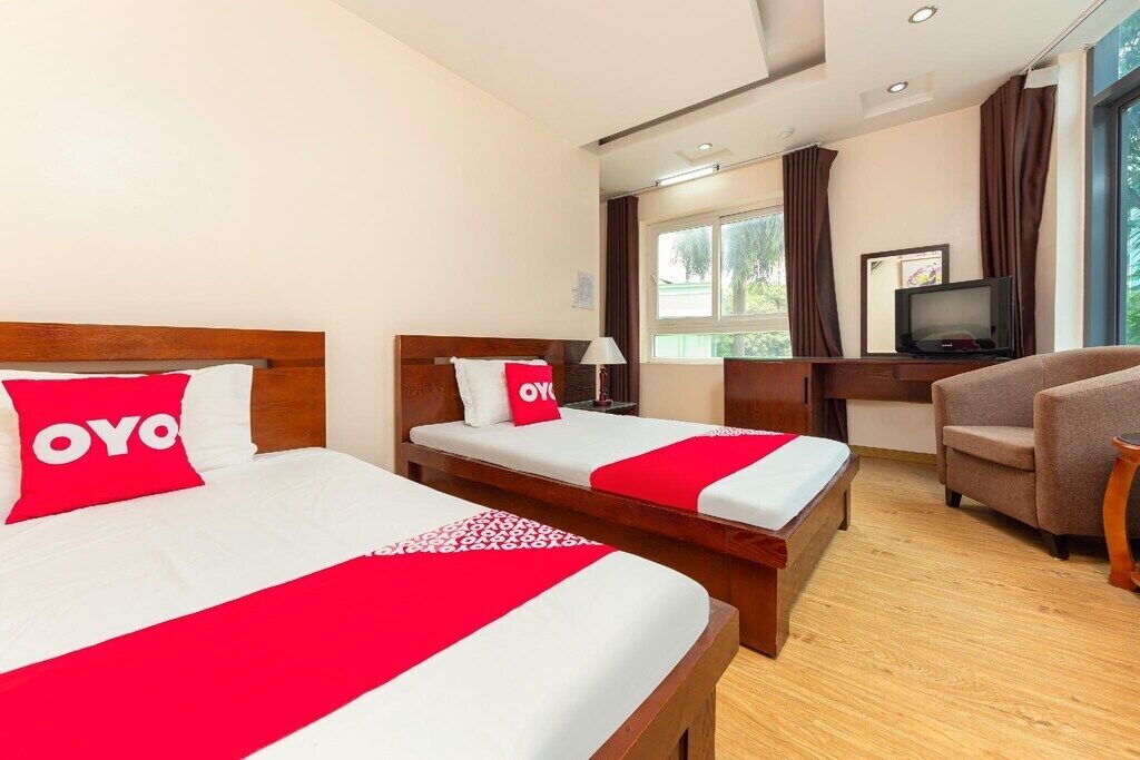 A hotel room with two beds, a TV, a desk, and a chair.