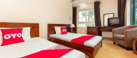 A hotel room with two beds, a TV, a desk, and a chair.