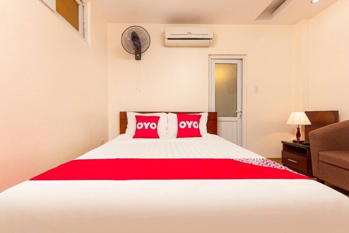 Une chambre d’hôtel avec un lit, une table de chevet, une lampe, un climatiseur et une porte.
