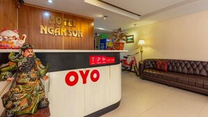 A hotel reception desk with a wooden panel and a large 'OYO' logo. - Mai Villa Ngan Son HN - by BAY LUXURY (Hanoi)