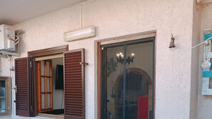 A building with a sliding glass door, a window with wooden shutters, and a tiled floor. - Adriano's beach house (Anzio)