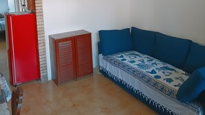 A living room with a blue sofa, a red refrigerator, a wooden cabinet, and a chandelier. - Adriano's beach house (Anzio)