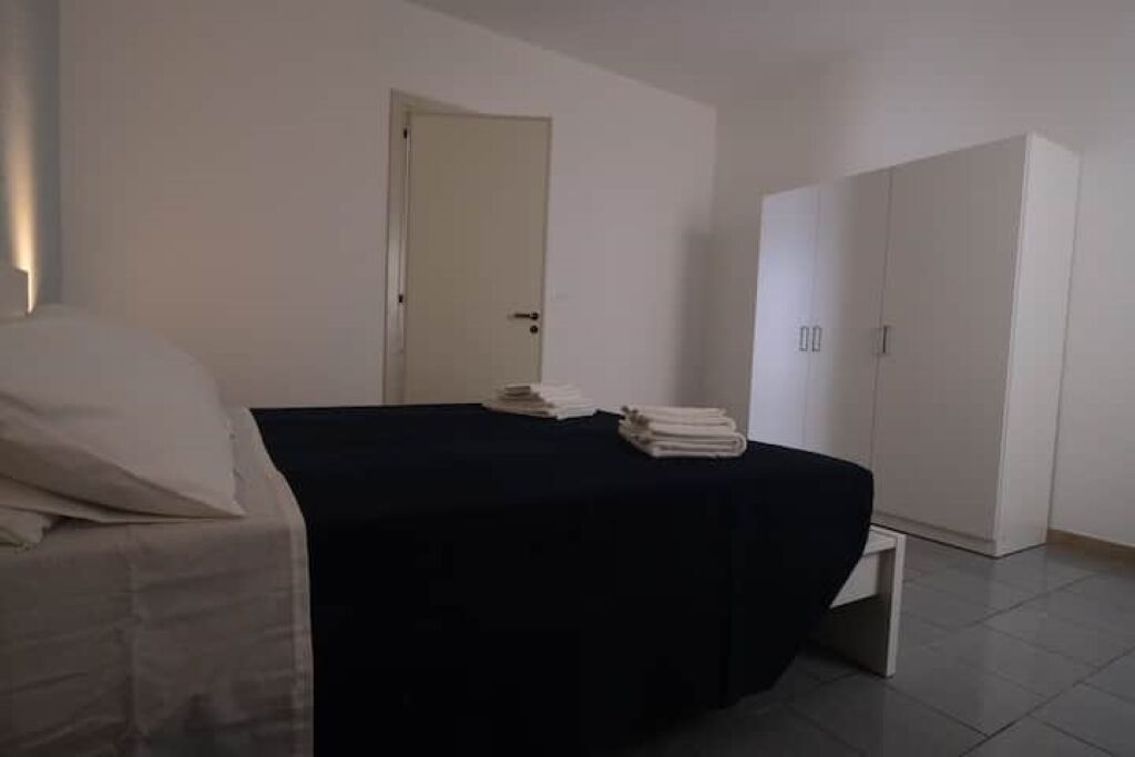 A hotel room with a bed, a small bedside table, a wardrobe, and a door.