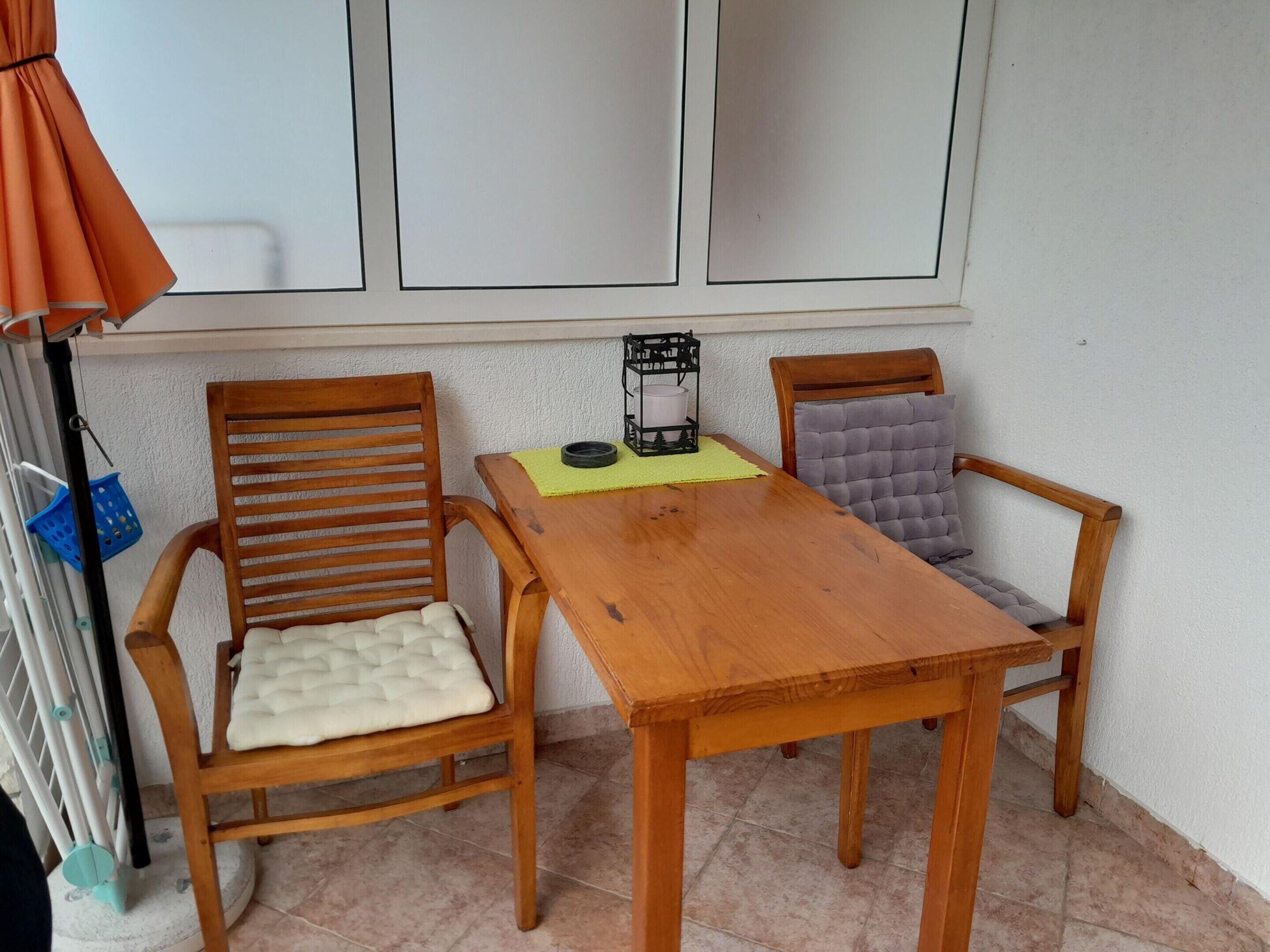 A wooden dining table with two chairs, a small table lamp, and a blue basket on the floor.
