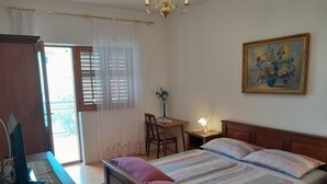 A bedroom with a bed, a desk, a chair, a lamp, and a painting on the wall. - Tranquil Retreat Near Drazica Beach (Biograd na Moru)