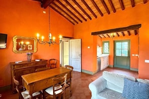 A dining area with a wooden table and chairs, a chandelier, and a mirror above the table. - App. Agriturismo Monteverde, Castelnuovo Magra (Castelnuovo Magra)