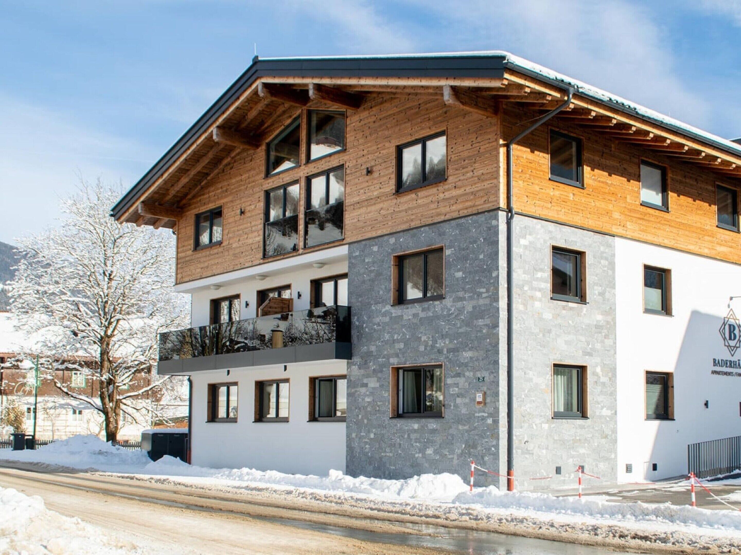 A modern multi-story building with a wooden facade and large windows.
