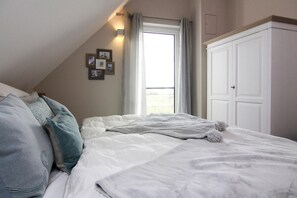 A bedroom with a bed, a window, and a wardrobe. - Ferienhaus Klint in Lancken (Dranske)