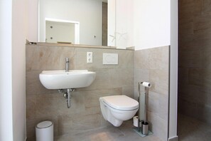 A modern bathroom with a sink, toilet, and hand dryer. - Ferienhaus Klint in Lancken (Dranske)