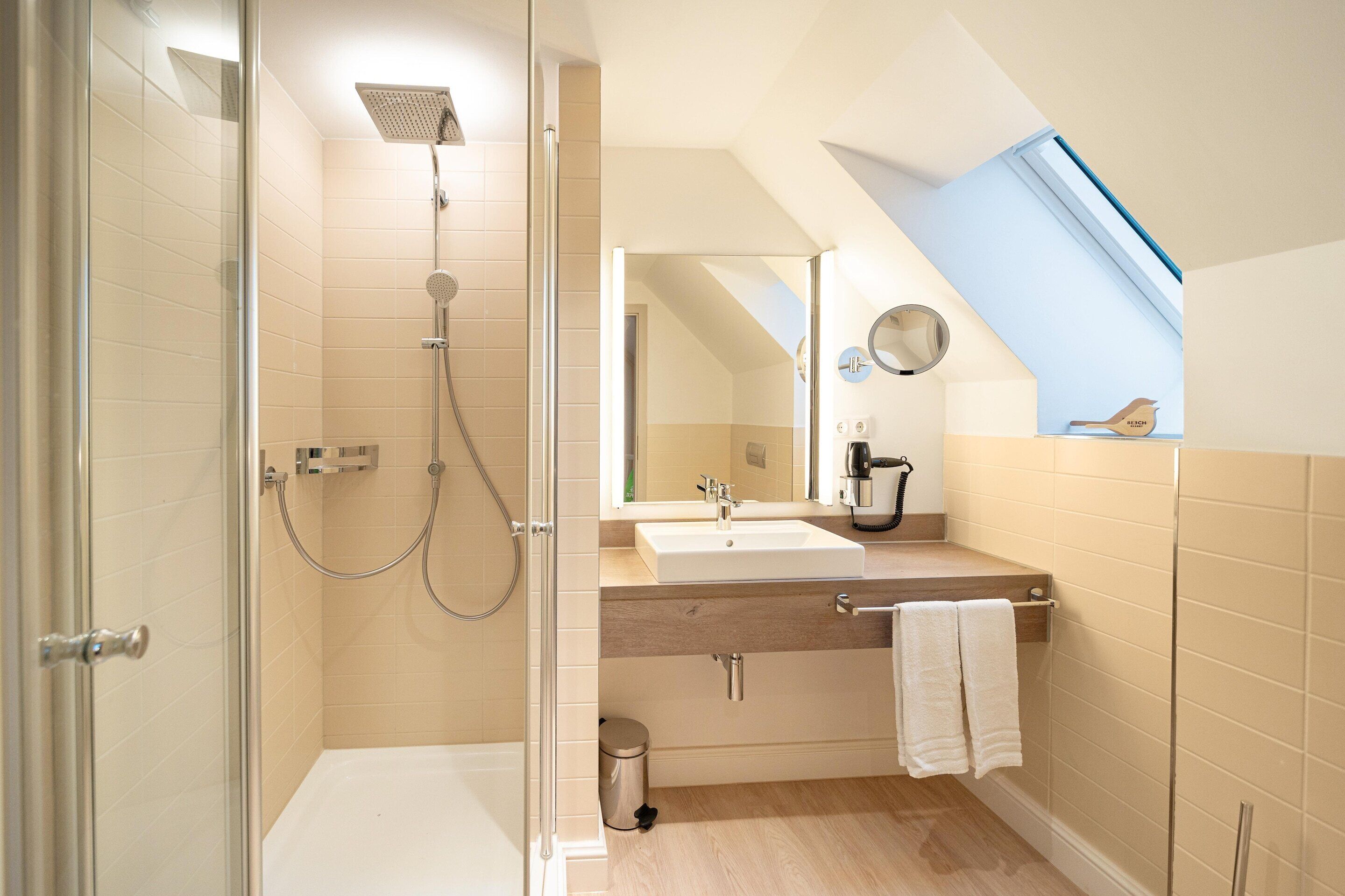 Een moderne badkamer met een douche, wastafel en spiegel.