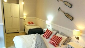Ein Schlafzimmer mit einem großen Bett, Nachttischen, einem Kleiderschrank und Wandleuchten.