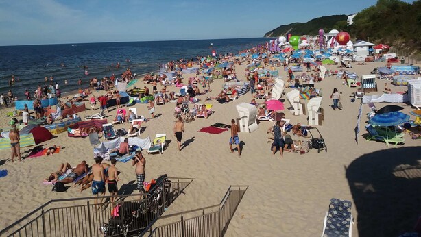 Ein überfüllter Strand mit vielen Sonnenschirmen und Liegestühlen.