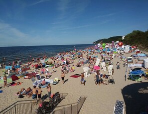 En fullsatt strand med många parasoller och strandstolar.