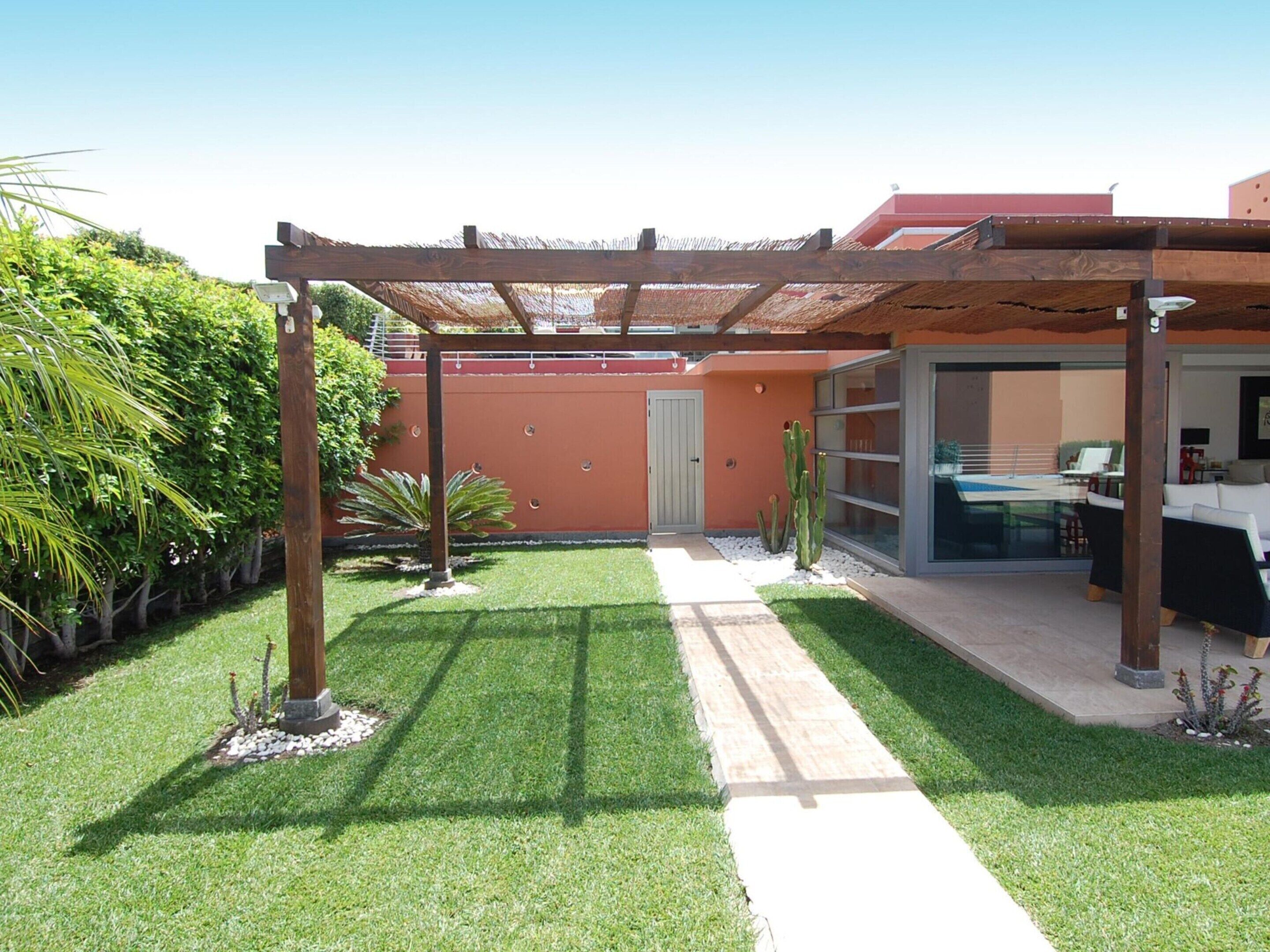 Zona patio con pergola, piscina e porta vetrata che dà su uno spazio esterno coperto.