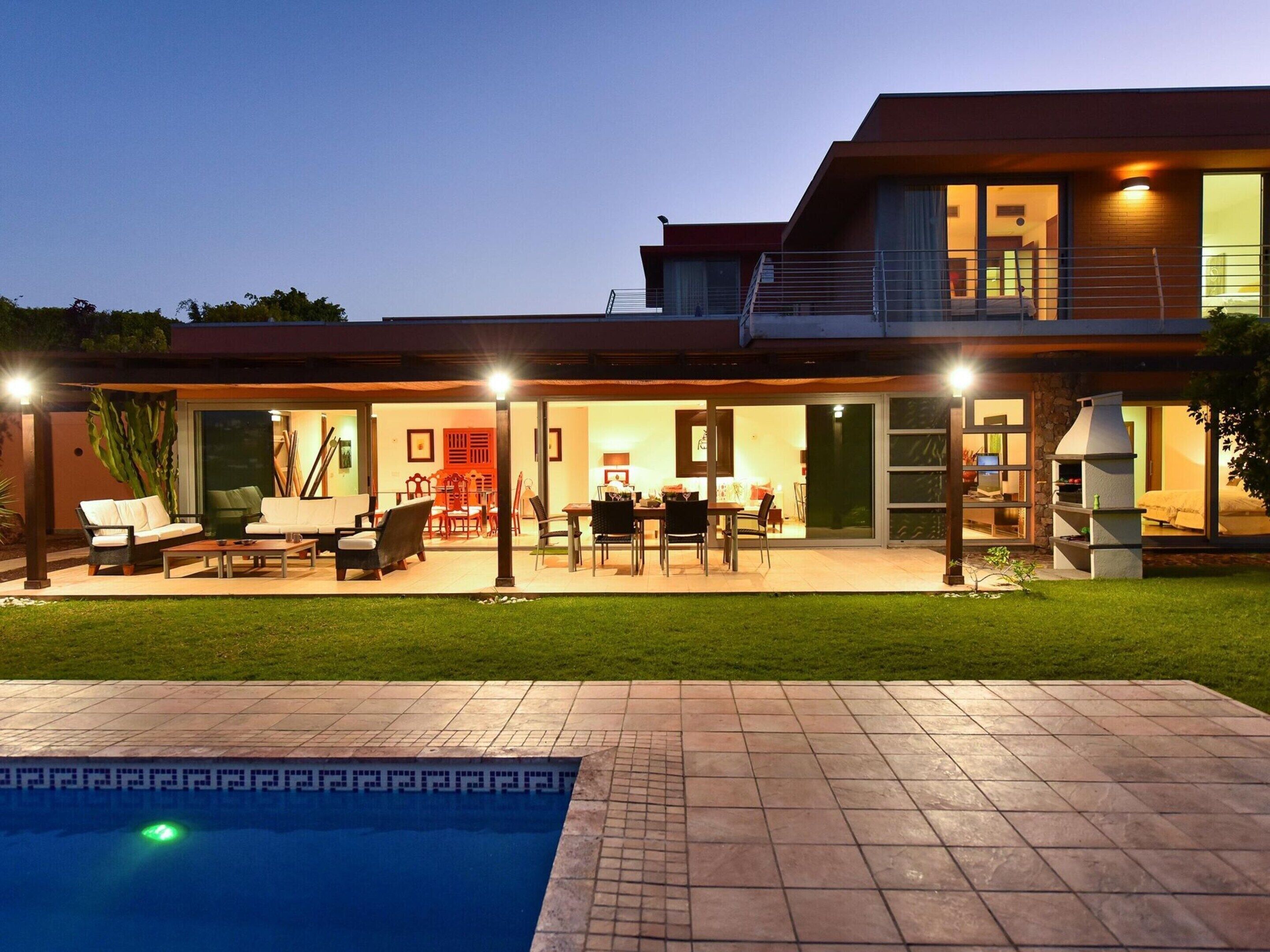 A modern house with a swimming pool, outdoor seating, and a barbecue area.