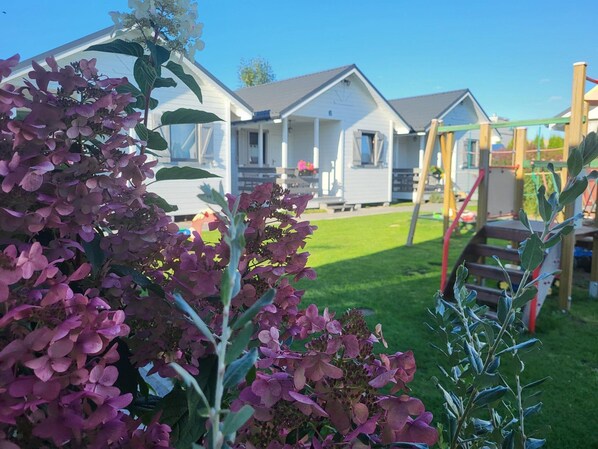 A residential area with a grassy lawn, a wooden swing set, and a row of white houses with grey roofs. - Holiday Homes Close to the Seaside Beach (Mielno)