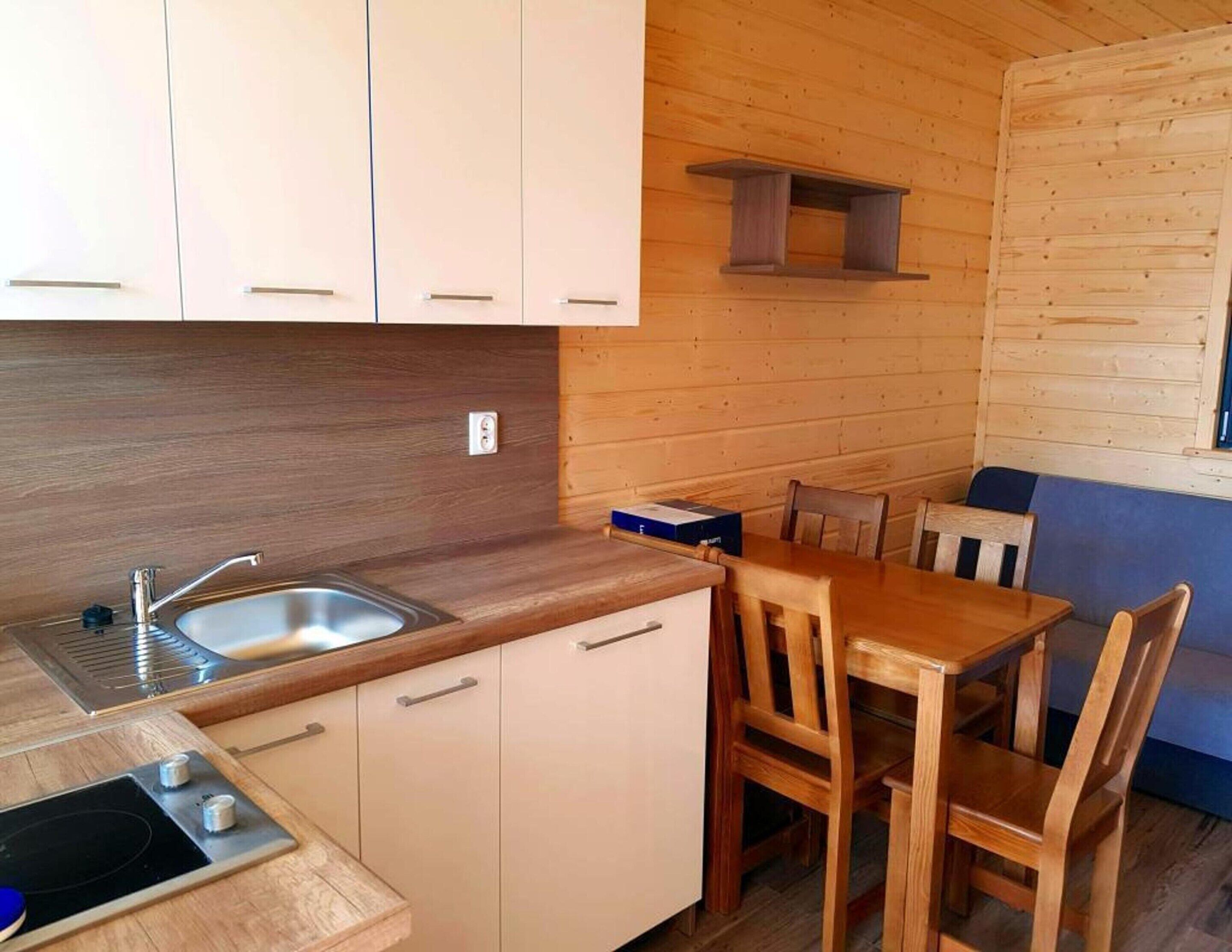 A compact kitchen with a sink, wooden cabinets, and a dining area with a table and chairs.