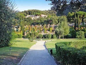 A pathway leading to a hillside villa complex with multiple buildings, surrounded by lush greenery and trees. - Apartment in Elba Near Bagnaia Beach (Rio)