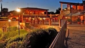 A hotel with a stone facade, outdoor seating, and a well-lit entrance. - Apartment in Residence Borgo Magliano, in Magliano (Magliano in Toscana)