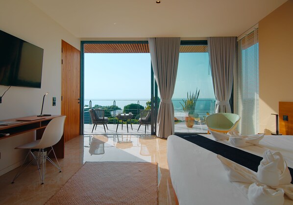 A modern hotel room with a large bed, a desk, and a balcony with a view of the sea. - STUNNING sea views - LUXURY villa - INFINITY pool (Koh Phangan)