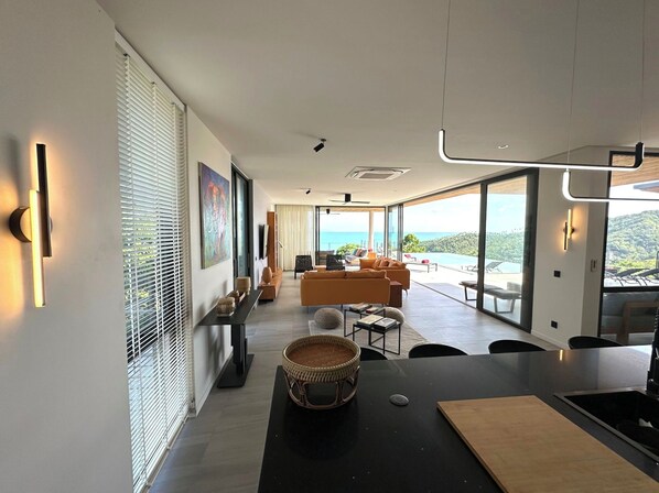 Una sala de estar moderna con un ventanal grande que ofrece vistas panorámicas, un comedor con una mesa negra y una acogedora zona de estar.