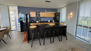 Een moderne keuken met een centraal eiland, barkrukken en een eethoek met een tafel en stoelen.