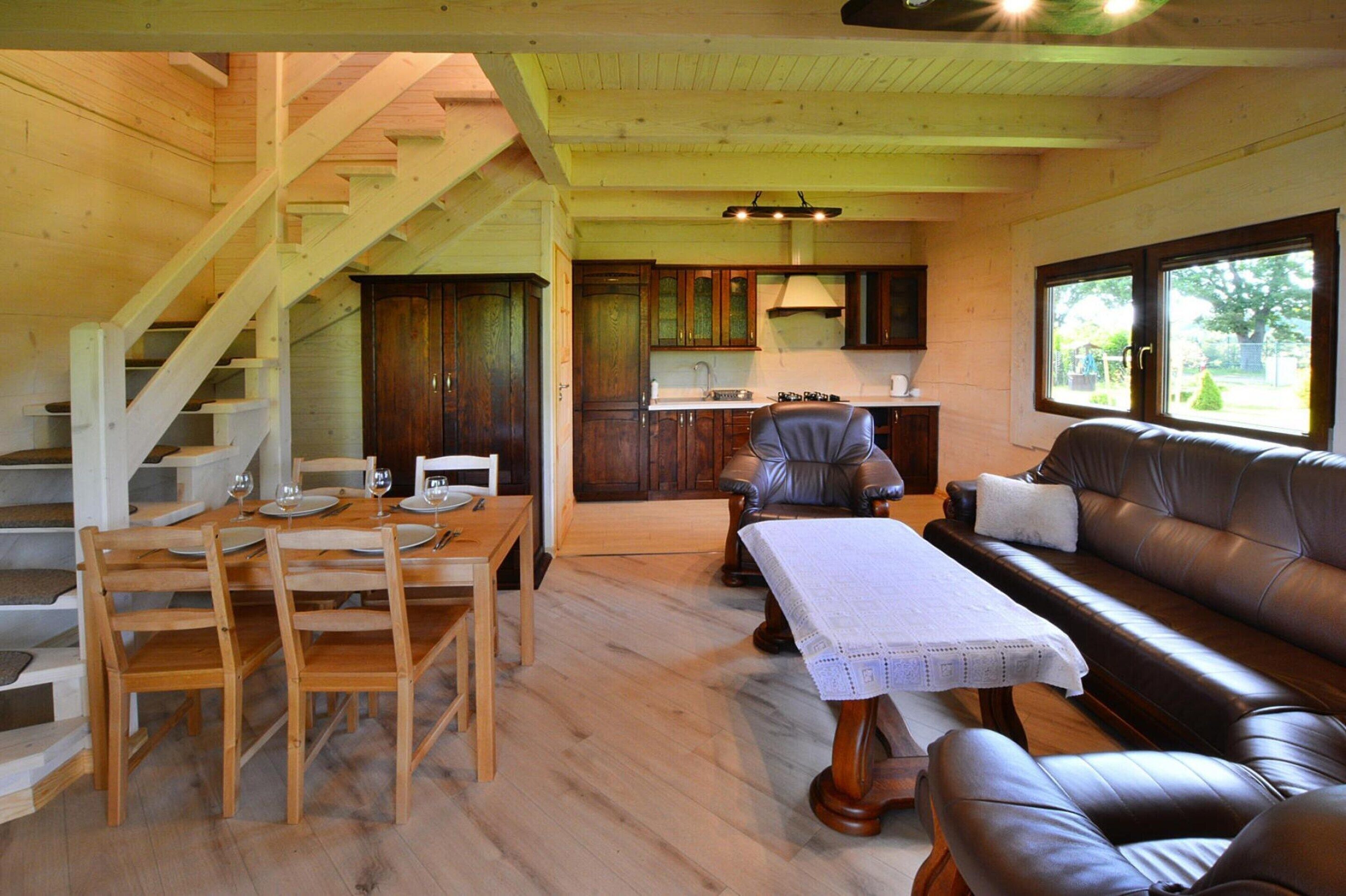 Interior de madeira com área de jantar, sofá e cozinha.