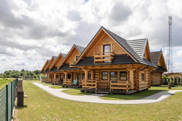 Una hilera de cabañas de madera con balcones, un sendero pavimentado y un espacio con césped.