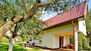 Una casa con techo de tejas rojas, un porche cubierto y un jardín.
