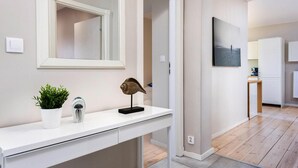 A modern kitchen with white cabinets, a wooden countertop, and a view into the dining area. - Apartment in Leba for Nature Lovers (Leba)