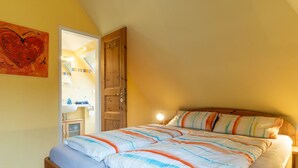 Ein Schlafzimmer mit einem hölzernen Bett, einem farbenfrohen Streifen-Kissen und einem großen abstrakten Gemälde an der Wand.