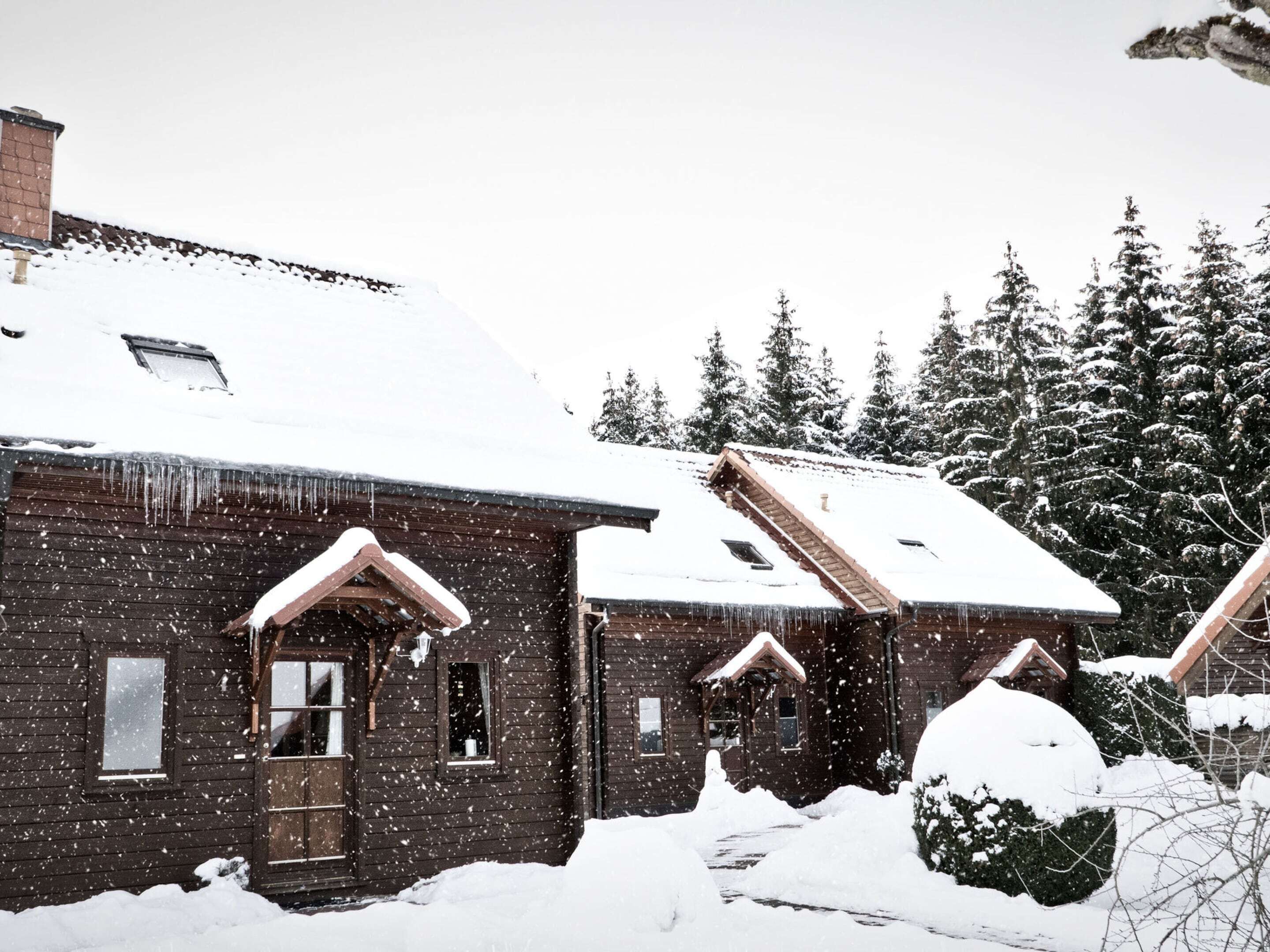A wooden cabin with a snow-covered roof and a small porch.