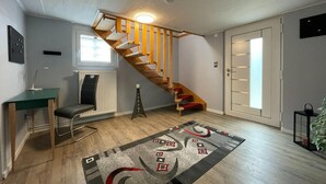 A modern interior with a wooden staircase, a desk, a chair, and a patterned rug. - Holiday Home in Walkenried With Sauna (Walkenried)
