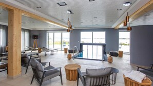 A modern indoor pool area with seating and a view of the outdoors. - Appartements im Maremuritz Yachthafen Resort (Waren (Müritz))
