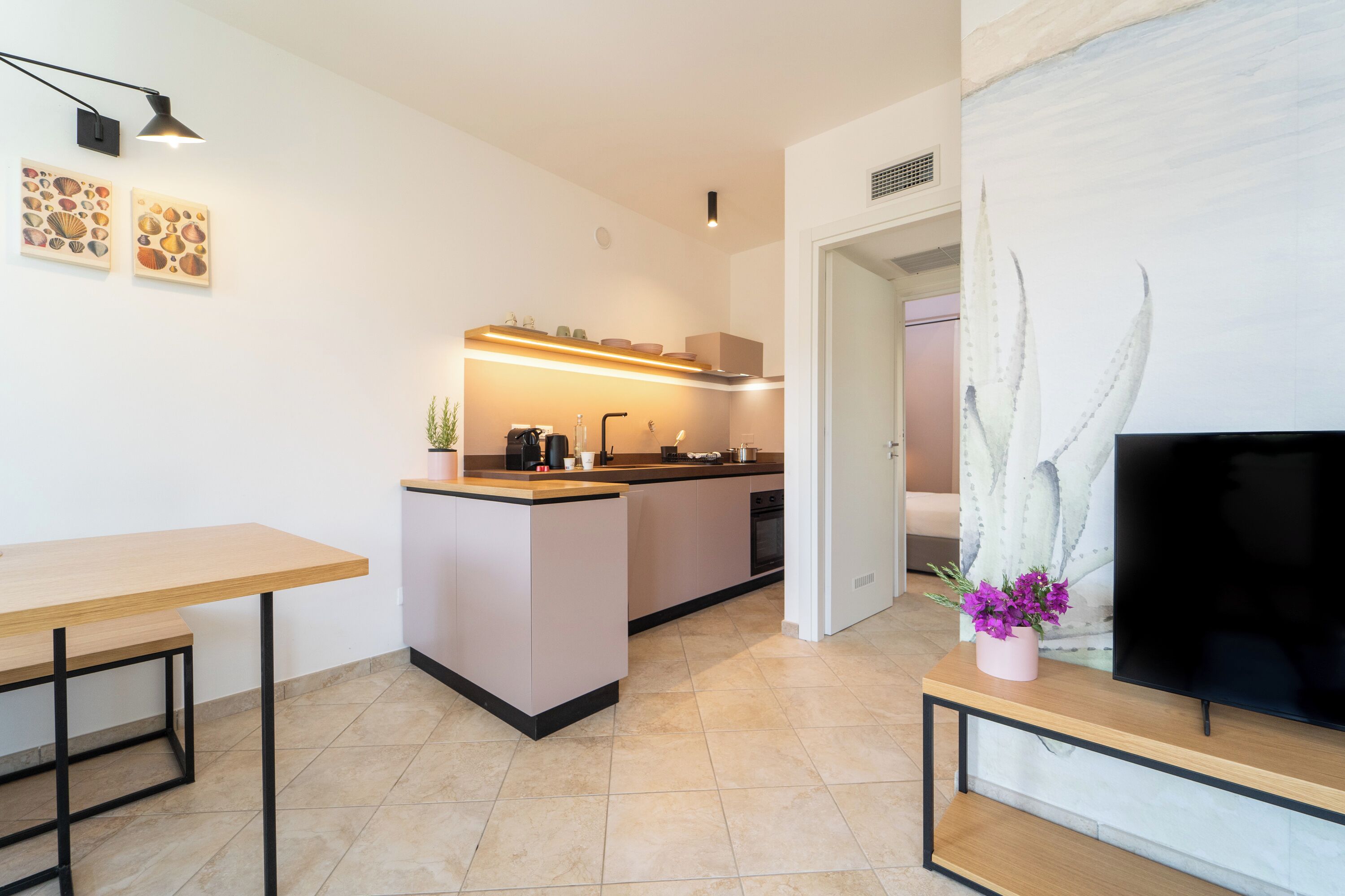 A modern kitchen with a central island, a dining table, and a flat-screen TV on a stand.
