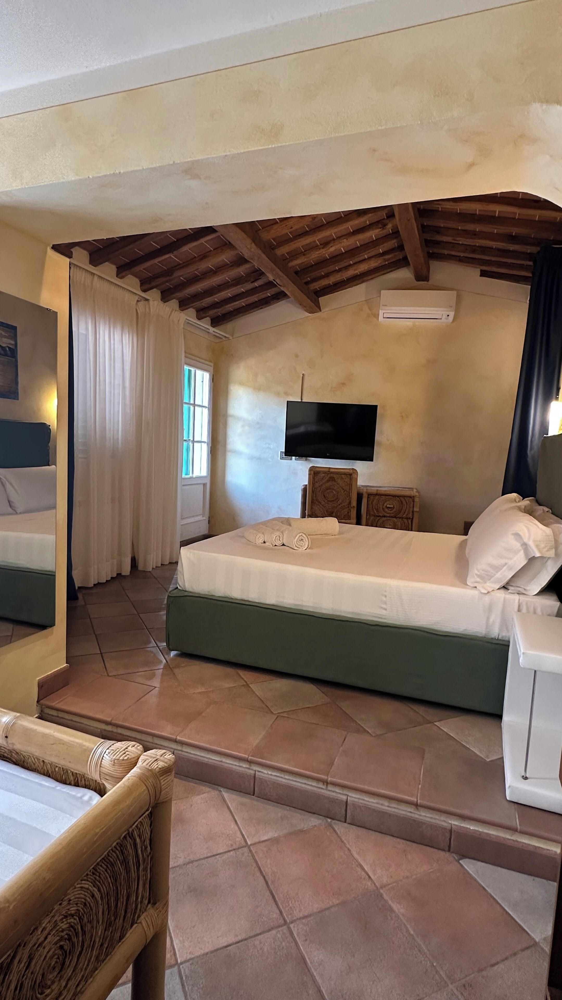 Una habitación con cama, televisión y ventana con cortinas.