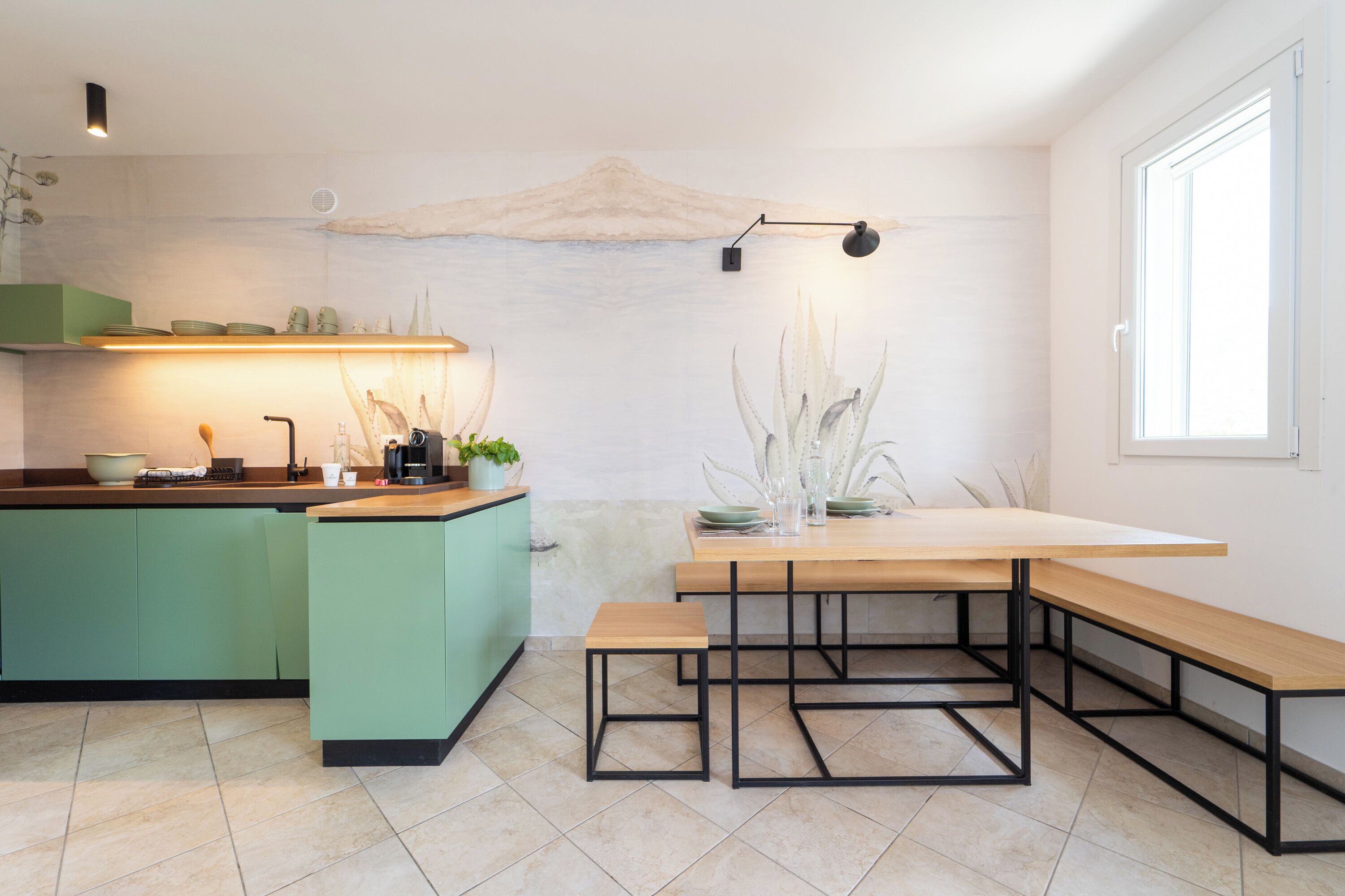 Una cocina moderna con una isla verde, una mesa de comedor de madera y un amplio ventanal.