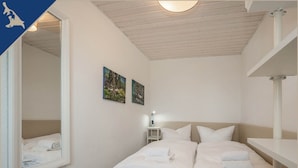 Un dormitorio con una cama, una mesita de noche y dos cuadros en la pared.