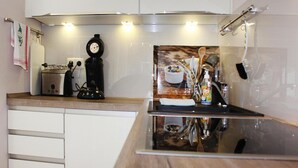 Una cucina con fornello, tostapane, macchina del caffè e una ciotola di frutta sul bancone.