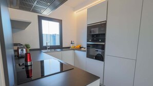 A modern kitchen with a black countertop, a built-in oven, and a window above the sink.