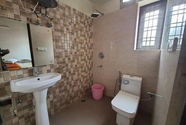Et badeværelse med flisebeklædt væg, vask, toilet og et vindue.