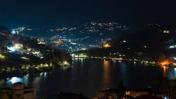 Vista nocturna de un pueblo a orillas del río, con edificios iluminados y un río tranquilo.