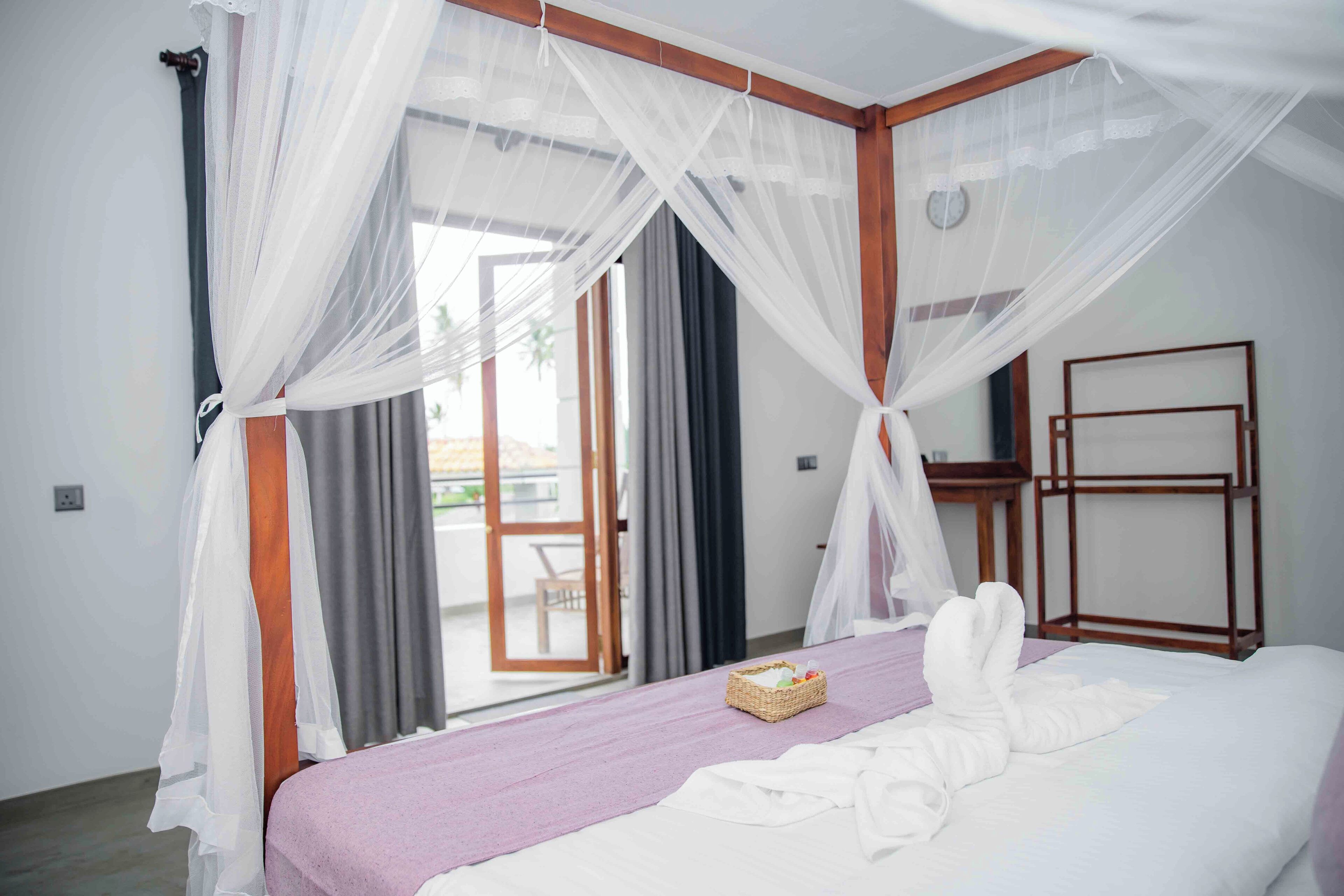 Un dormitorio con cama, mesita de noche, ventana con cortinas y vista al exterior.