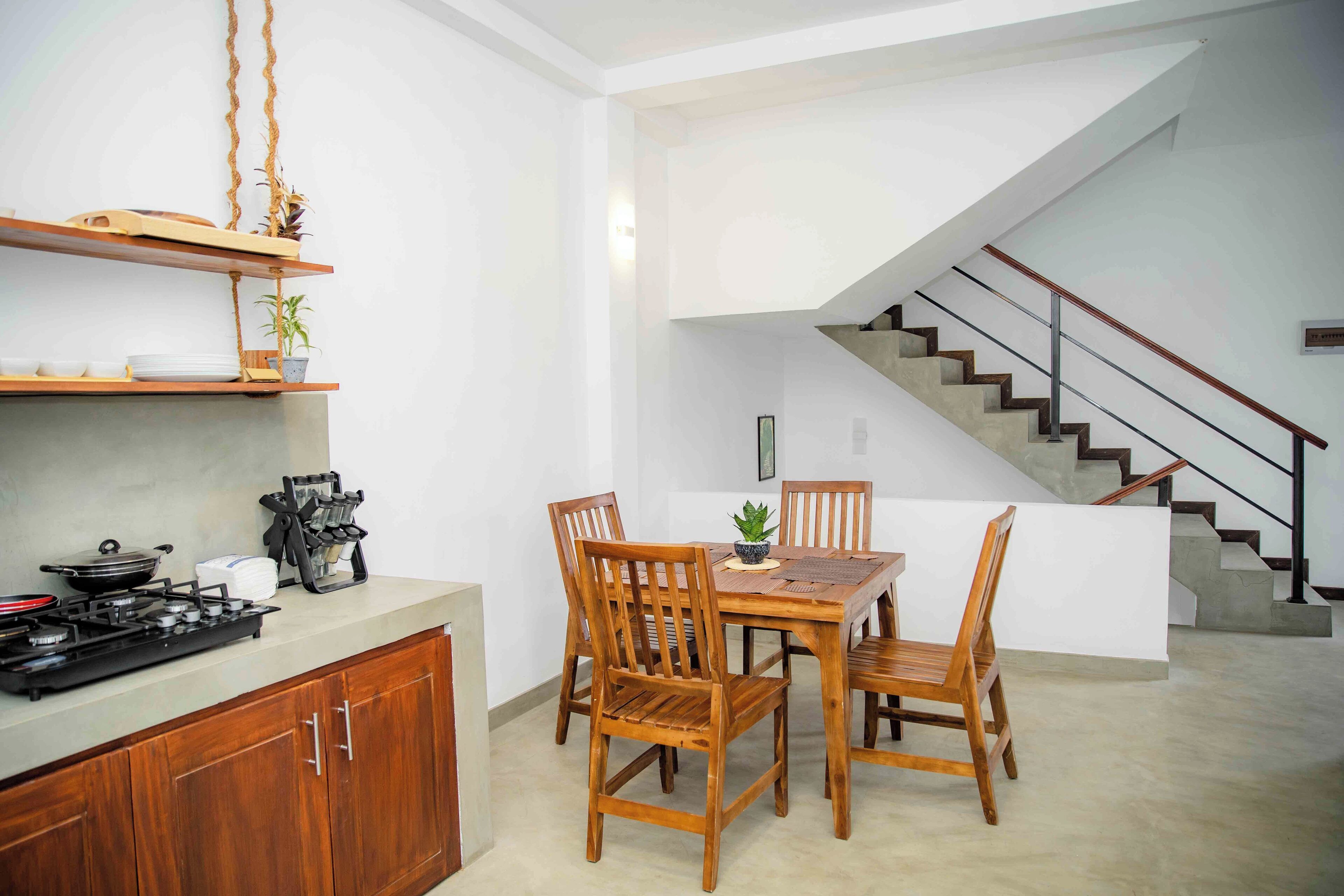 A modern kitchen with wooden cabinets, a gas stove, and a dining area with wooden chairs and a table.